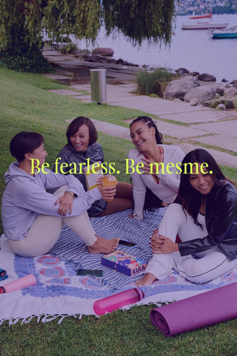 Four women sitting on a blanket by a lake with text 'Be fearless. Be mesme.'